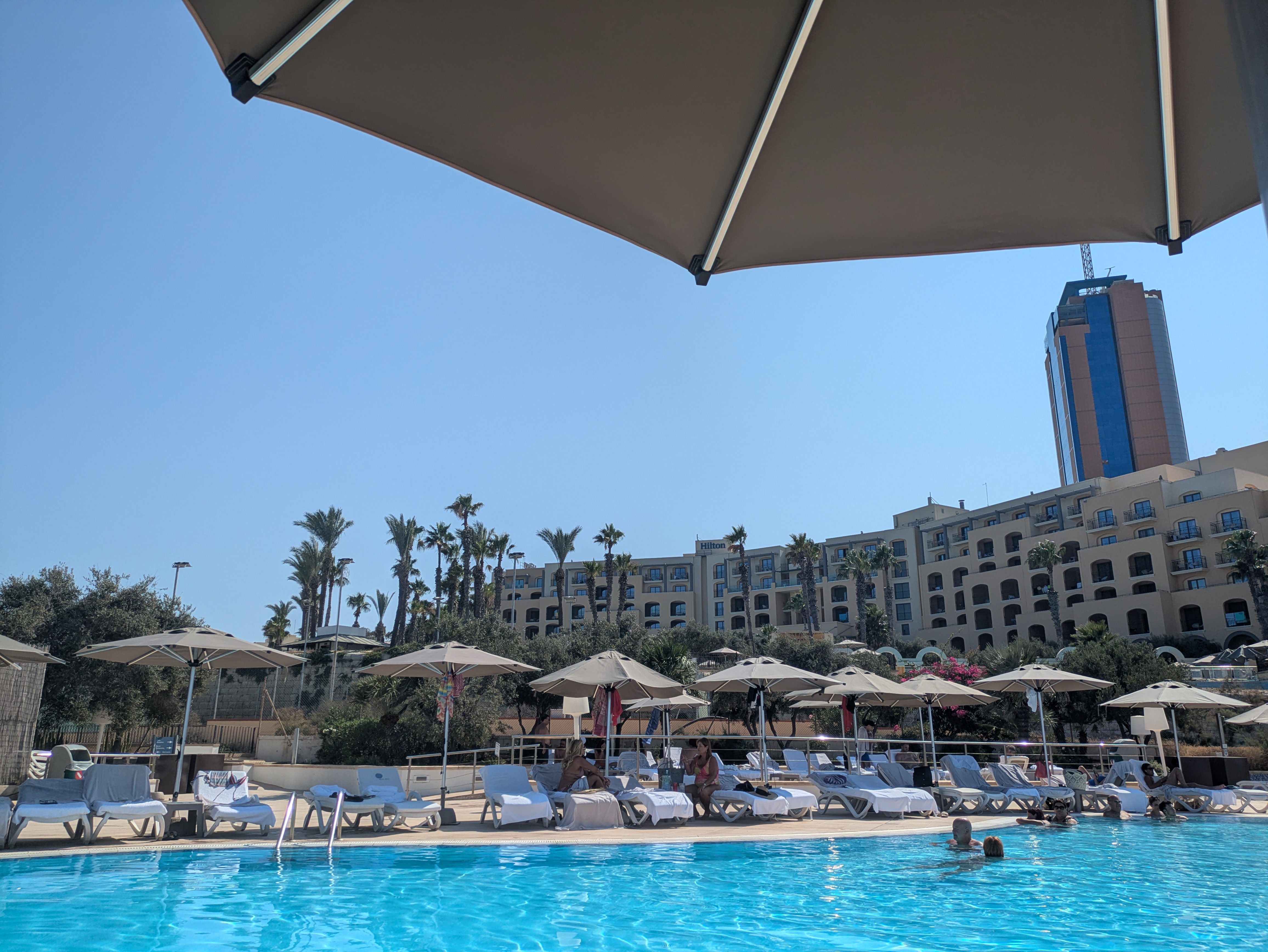 Photo of Hilton Malta pool at Beach Club with umbrellas